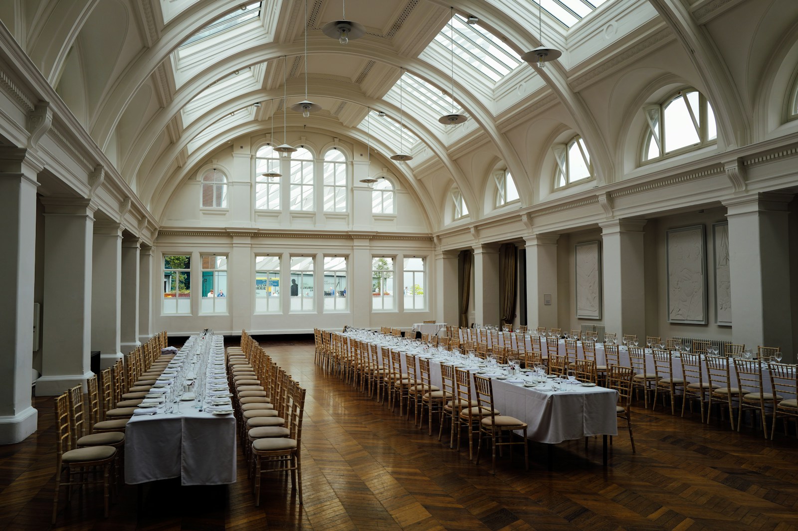 Long tables set for a banquet in a grand hall.